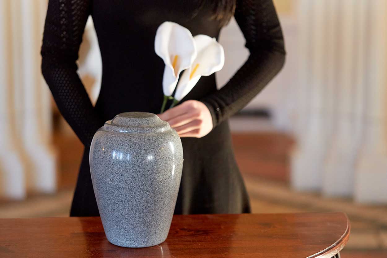 a girl holding a flower beside ash jar