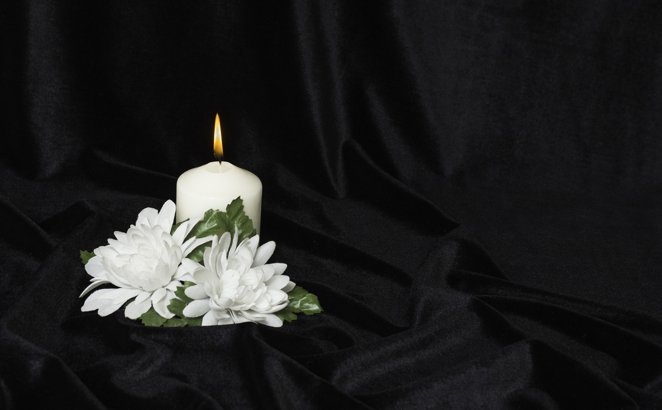 White burning candle and white flowers